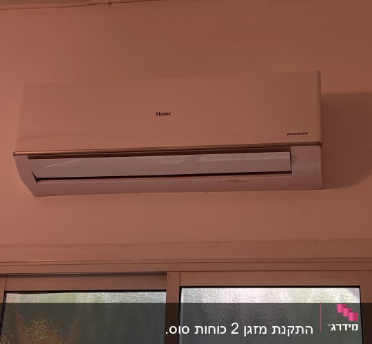 מזגן קיר לבן מותקן מעל חלון זכוכית